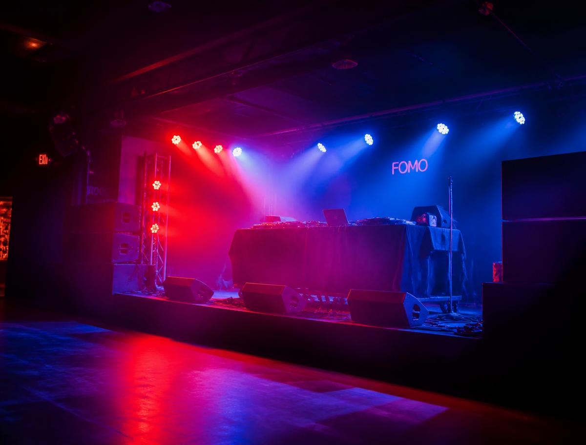 Showcase venue stage with DJ booth under red and blue lighting