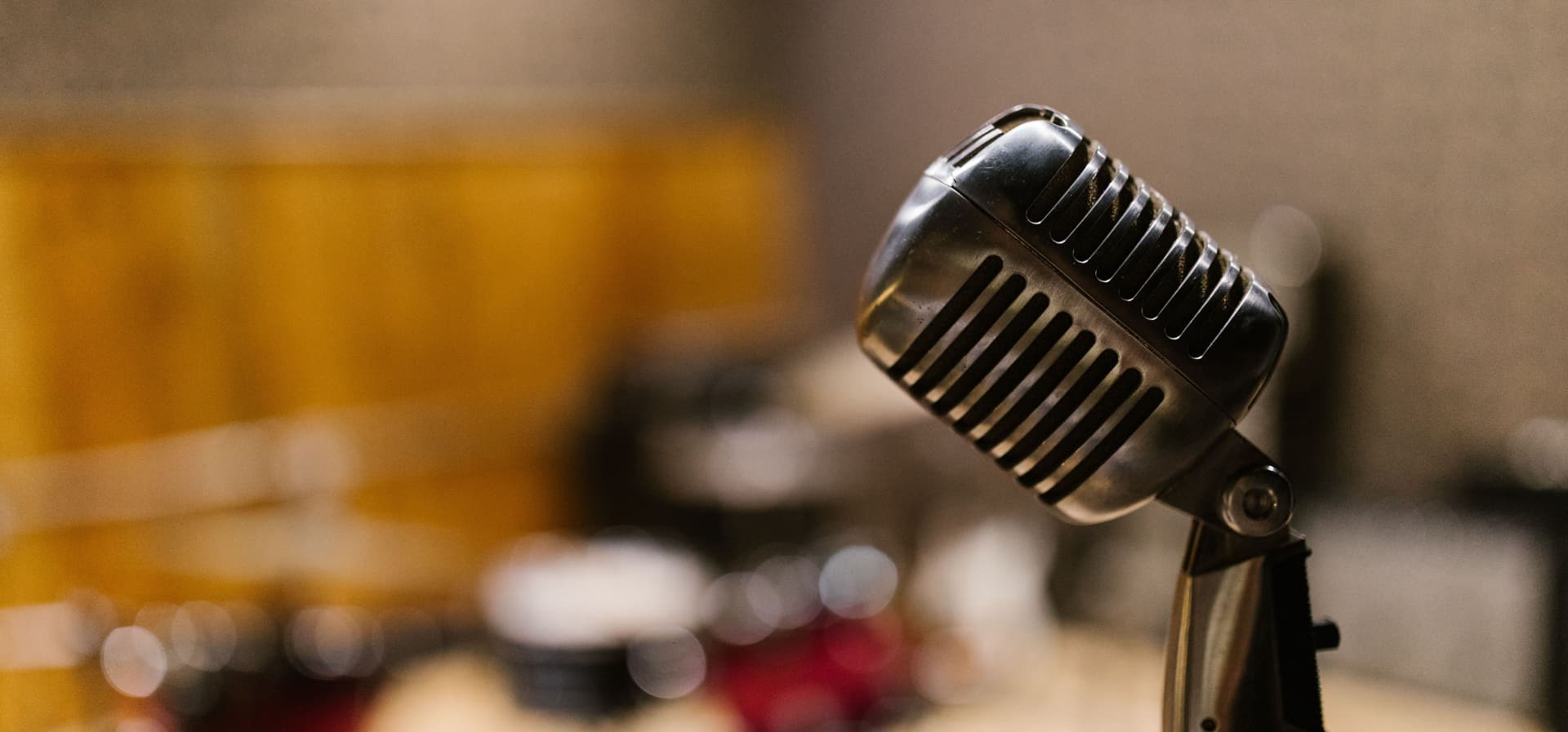 Vintage silver studio microphone in a warm-lit recording room