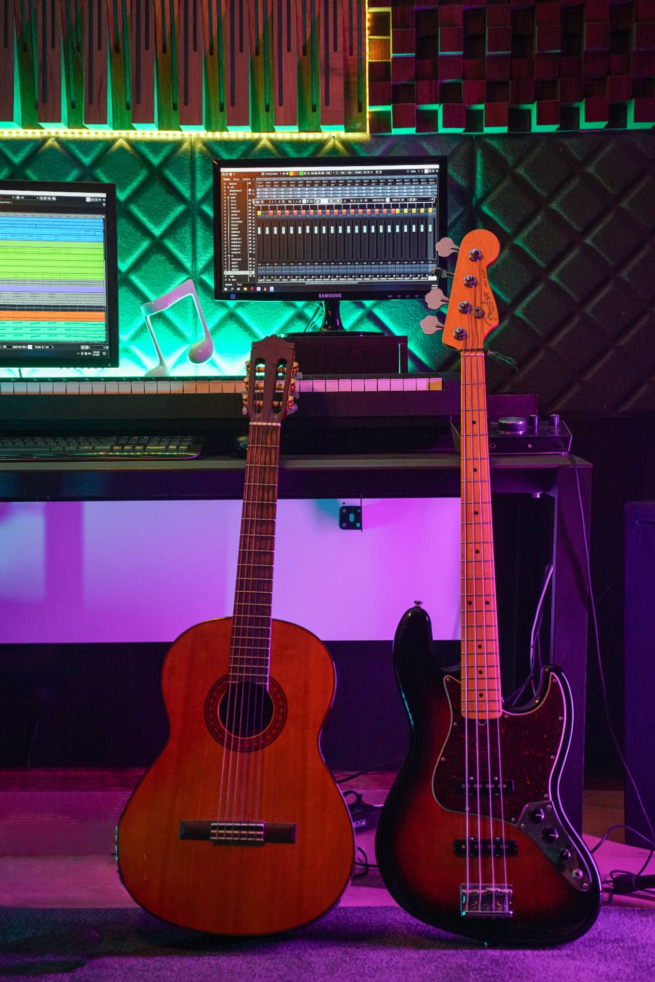 Acoustic and bass guitars resting in a neon-lit home recording studio