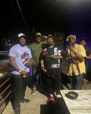 Five men posing together at night in an outdoor venue
