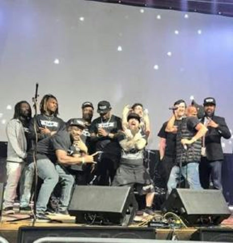 A group of performers posing on stage in matching Space Tunez shirts