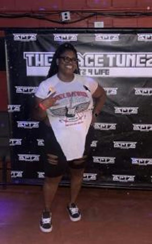 A smiling artist posing in front of a The Space Tunez step-and-repeat backdrop