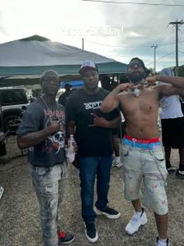 Three men posing outdoors under an event canopy for a Fourth of July post